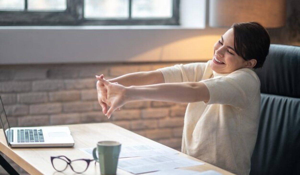 pleased-female-doing-wrist-stretches-desk_259150-60501